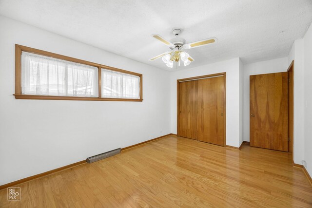 empty room with a textured ceiling, ceiling fan, and light hardwood / wood-style floors