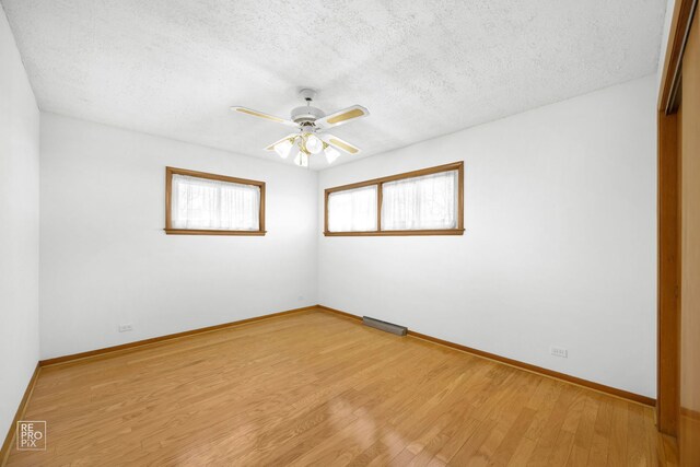 spare room with a textured ceiling and light wood-type flooring