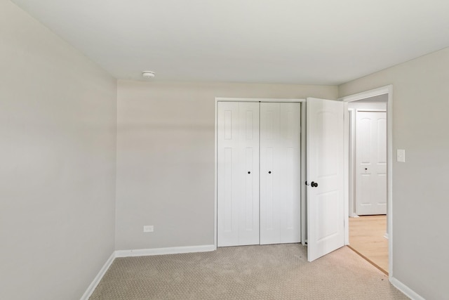 unfurnished bedroom with light colored carpet and a closet