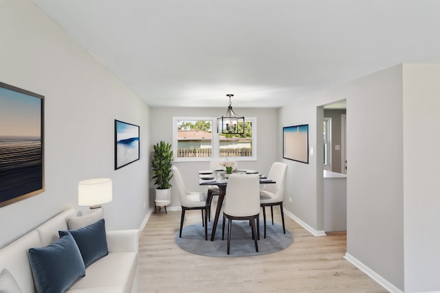 dining space featuring light wood-type flooring and a chandelier