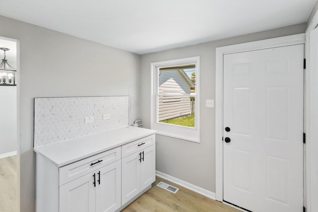 doorway with a chandelier and light hardwood / wood-style flooring