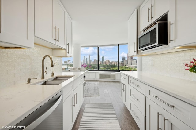 kitchen with sink, light stone counters, appliances with stainless steel finishes, dark hardwood / wood-style flooring, and white cabinetry