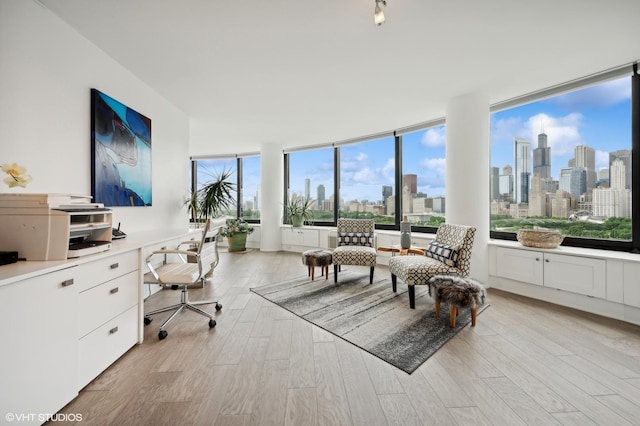 home office with built in desk and light hardwood / wood-style floors