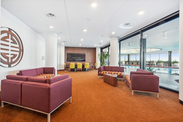 carpeted living room featuring floor to ceiling windows and brick wall