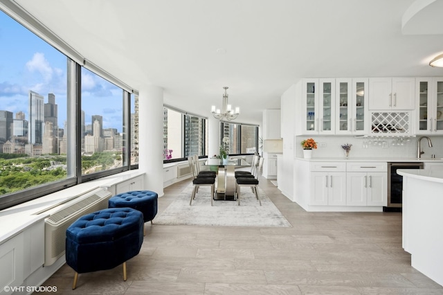 dining space featuring sink, an inviting chandelier, beverage cooler, and light wood-type flooring