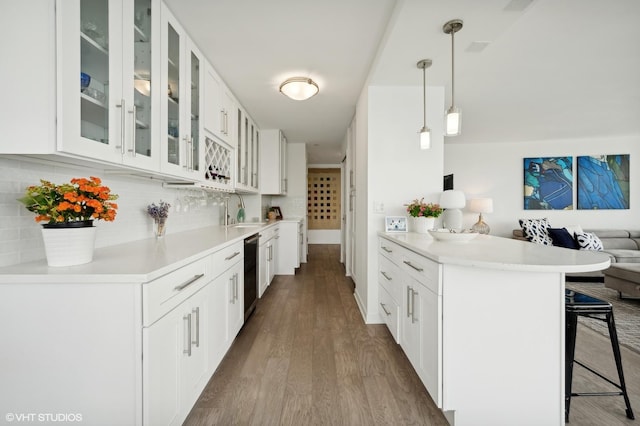 kitchen with a breakfast bar, white cabinets, sink, hanging light fixtures, and decorative backsplash