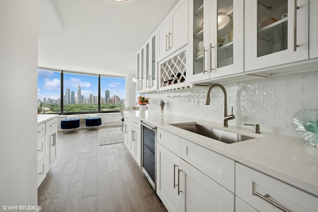 kitchen featuring sink, wine cooler, light stone counters, decorative backsplash, and white cabinets