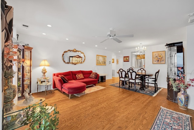 living room with ceiling fan with notable chandelier and wood-type flooring