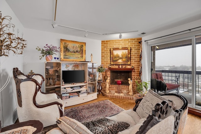 living room with a brick fireplace, hardwood / wood-style flooring, and rail lighting