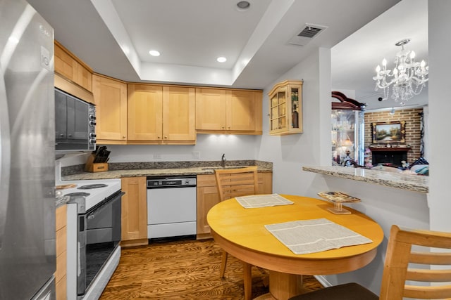 kitchen featuring white appliances, kitchen peninsula, light brown cabinetry, and light stone countertops