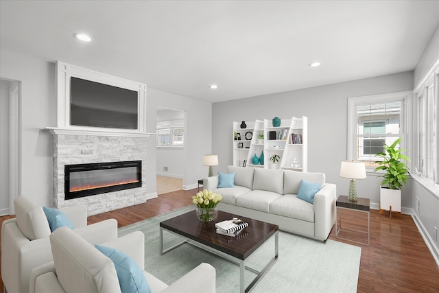 living room with hardwood / wood-style floors and a stone fireplace