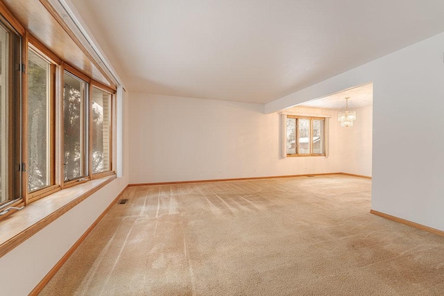 carpeted spare room featuring a notable chandelier