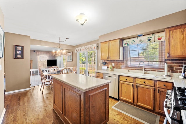 kitchen featuring pendant lighting, dishwasher, stove, sink, and a notable chandelier