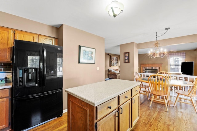 kitchen featuring a center island, black refrigerator with ice dispenser, light hardwood / wood-style flooring, a notable chandelier, and decorative light fixtures