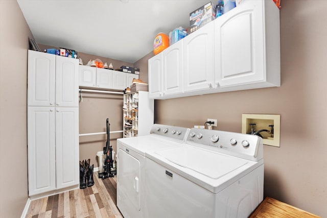 washroom featuring washing machine and clothes dryer, light hardwood / wood-style flooring, and cabinets