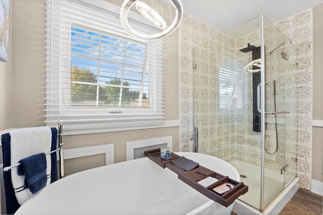 bathroom with hardwood / wood-style floors, independent shower and bath, and an inviting chandelier