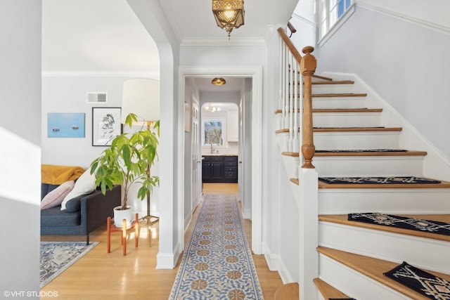 staircase featuring ornamental molding and wood-type flooring