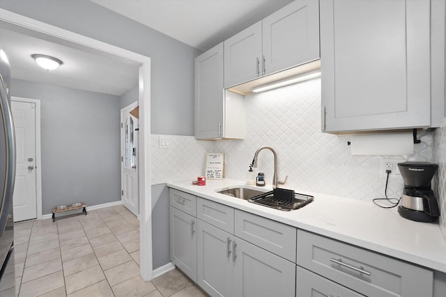 kitchen featuring tasteful backsplash, gray cabinetry, sink, and light tile patterned floors