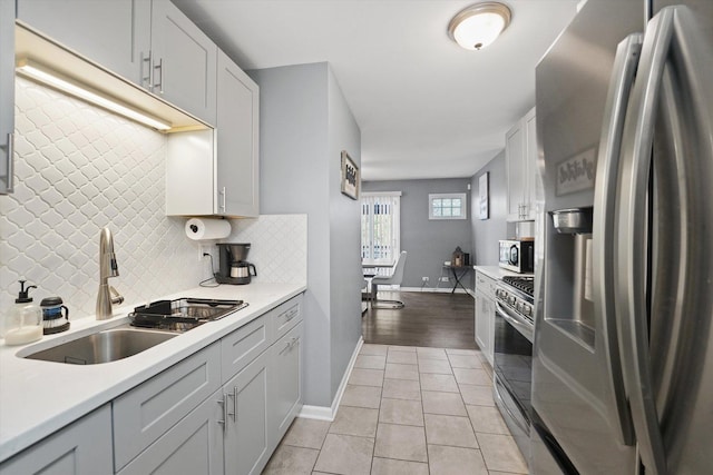 kitchen featuring white cabinetry, sink, tasteful backsplash, light tile patterned floors, and appliances with stainless steel finishes