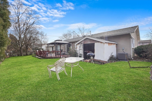 back of house featuring a gazebo, a wooden deck, a lawn, and central AC