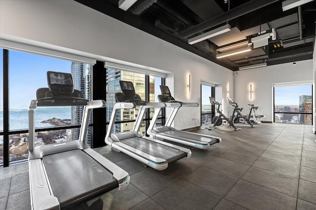 workout area with a high ceiling and a water view