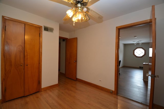 unfurnished bedroom featuring ceiling fan, light hardwood / wood-style floors, and a closet