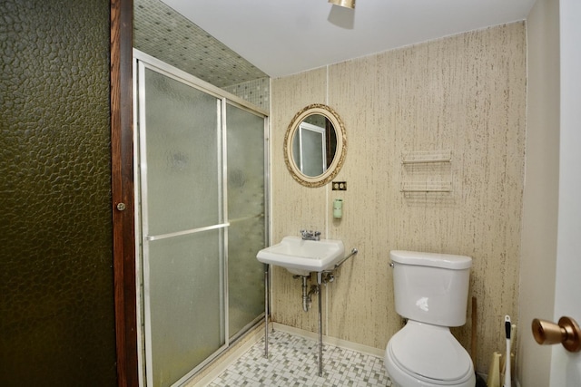 bathroom with toilet, a shower with door, and sink