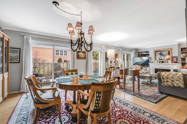 dining room with an inviting chandelier, ornamental molding, and light hardwood / wood-style floors