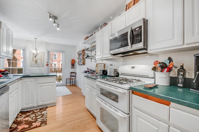 kitchen with appliances with stainless steel finishes, decorative light fixtures, light wood-type flooring, a chandelier, and white cabinets