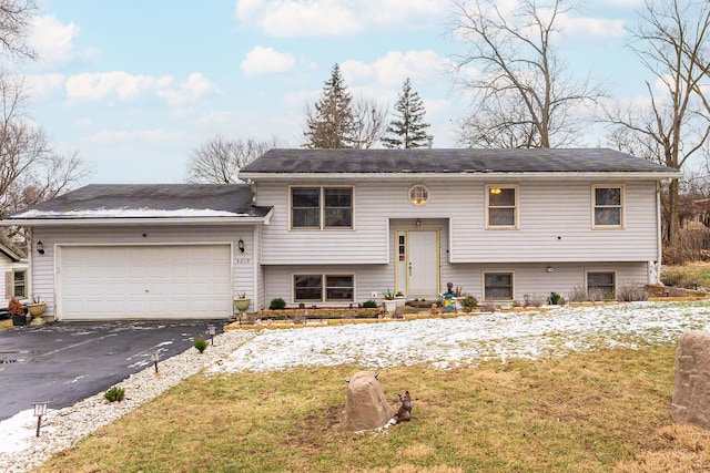 bi-level home featuring a garage and a front lawn