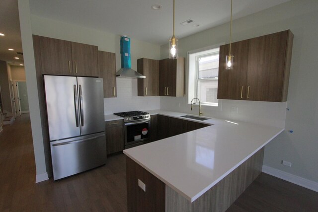 kitchen with stainless steel appliances, wall chimney exhaust hood, sink, light hardwood / wood-style flooring, and decorative light fixtures