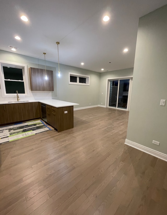 kitchen with sink, hanging light fixtures, hardwood / wood-style floors, and kitchen peninsula