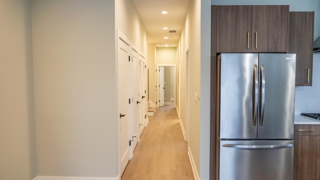 kitchen featuring tasteful backsplash, light hardwood / wood-style flooring, stainless steel fridge, and dark brown cabinetry