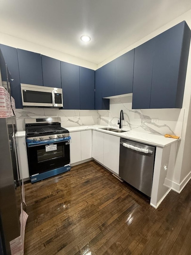 kitchen with dark wood-type flooring, blue cabinets, sink, white cabinetry, and stainless steel appliances