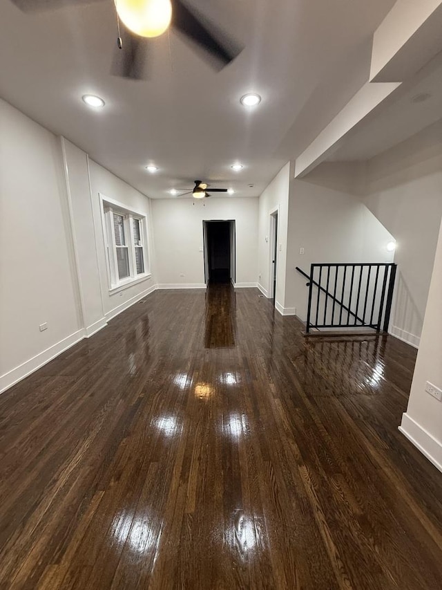 unfurnished living room with ceiling fan and dark wood-type flooring