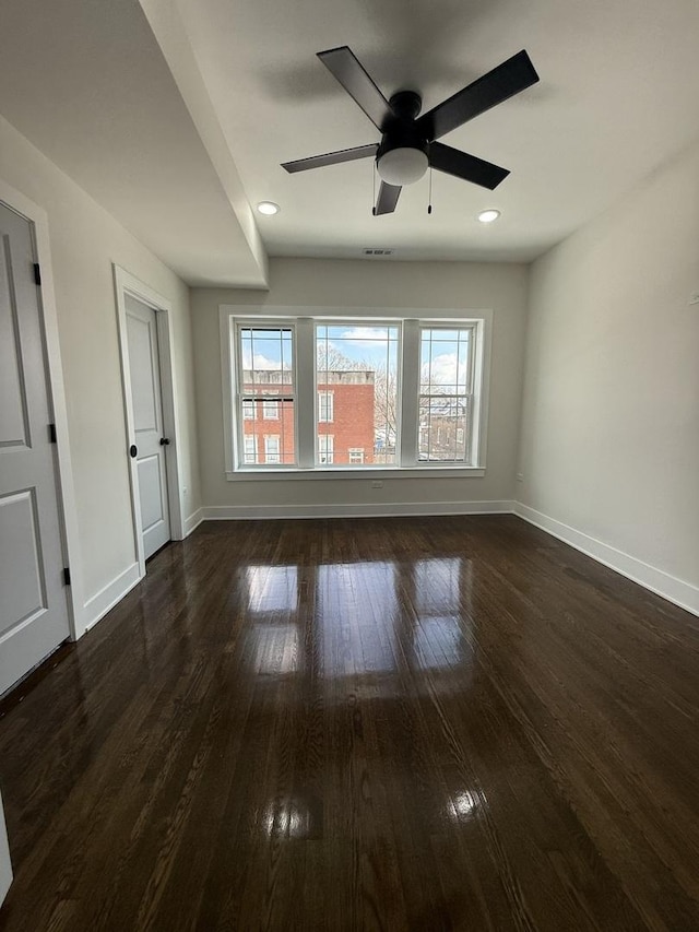 empty room with ceiling fan and dark wood-type flooring