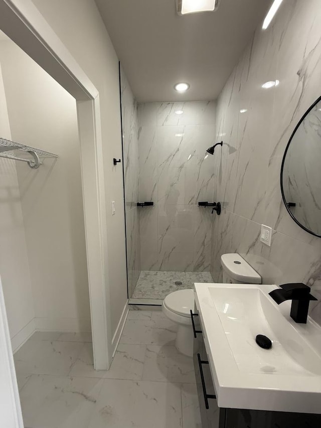 bathroom featuring toilet, a tile shower, tile walls, and vanity