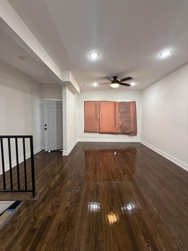 unfurnished living room featuring ceiling fan and dark wood-type flooring