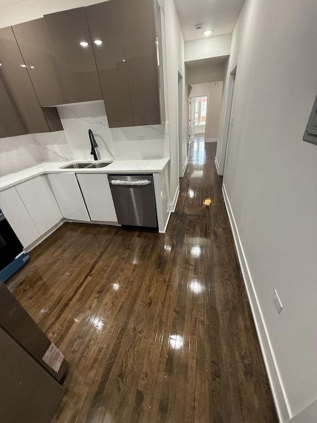 kitchen with dishwasher, sink, light stone counters, dark hardwood / wood-style flooring, and backsplash