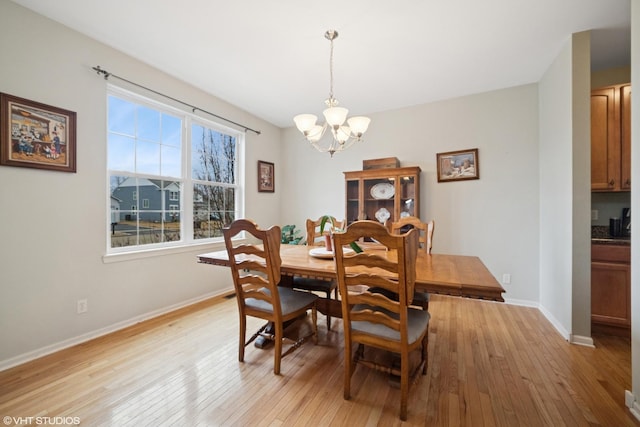 dining room with a chandelier, light wood-style flooring, and baseboards