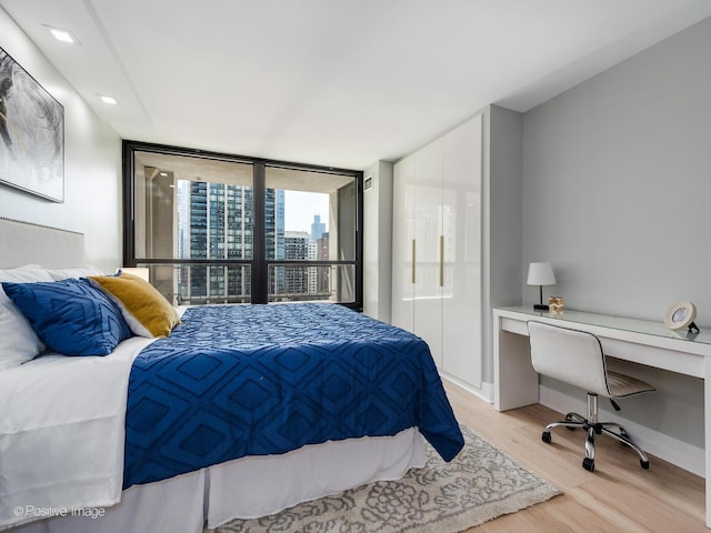 bedroom featuring built in desk, light hardwood / wood-style floors, and floor to ceiling windows