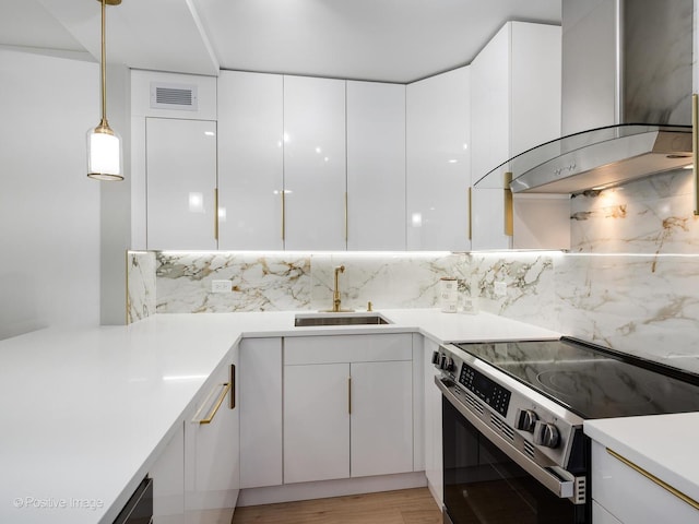 kitchen with sink, white cabinetry, stainless steel electric range oven, and wall chimney range hood