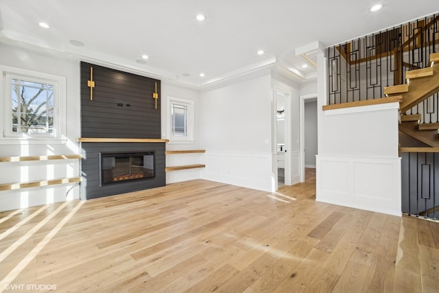 unfurnished living room with a fireplace, light wood-type flooring, plenty of natural light, and ornamental molding