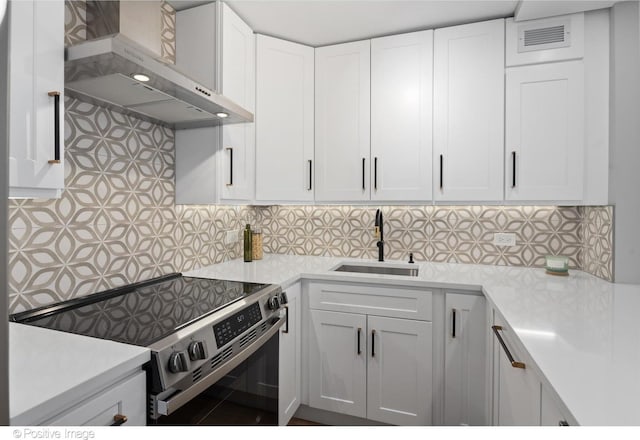 kitchen featuring sink, white cabinetry, stainless steel range with electric stovetop, and wall chimney range hood