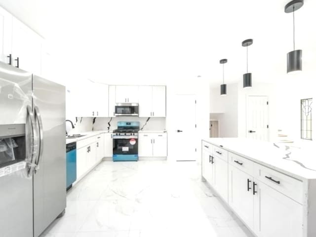 kitchen featuring appliances with stainless steel finishes, pendant lighting, sink, white cabinets, and light stone counters