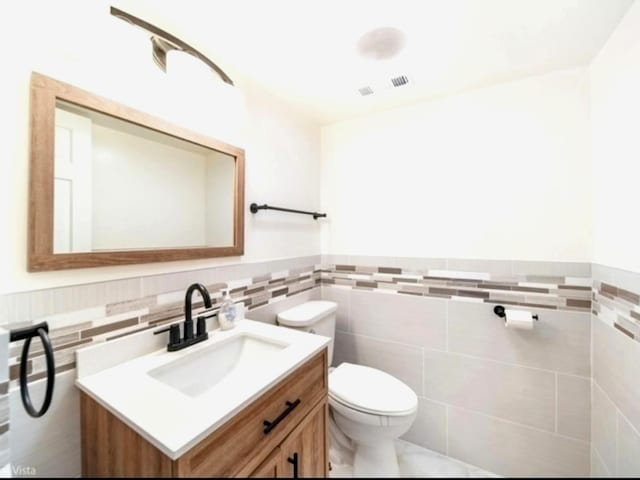 bathroom with vanity, tile walls, and toilet