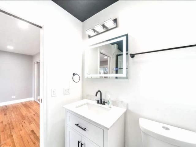 bathroom featuring vanity, wood-type flooring, and toilet