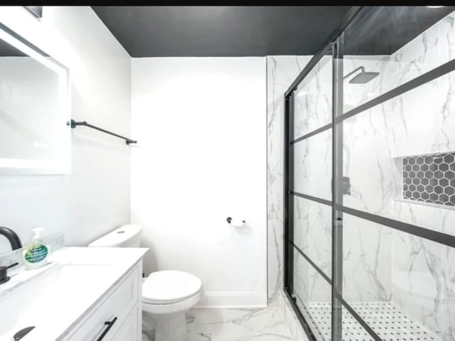 bathroom featuring a shower with door, vanity, and toilet