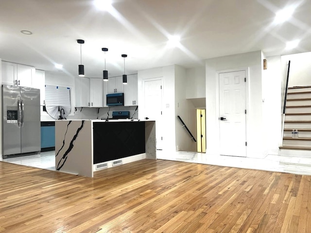 kitchen featuring stainless steel refrigerator with ice dispenser, white cabinetry, decorative light fixtures, and kitchen peninsula