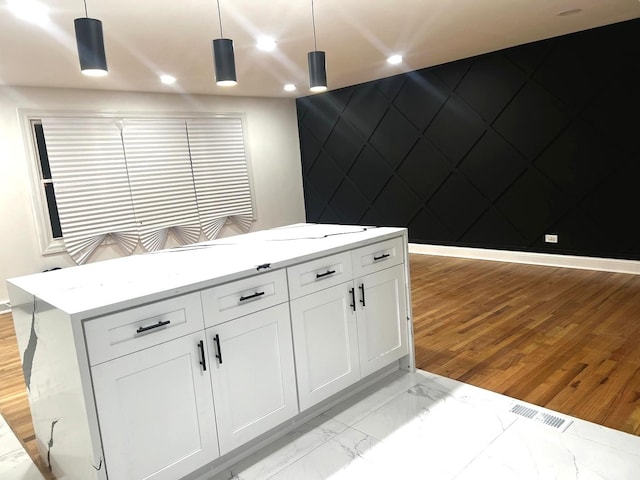 kitchen with pendant lighting, white cabinetry, light stone counters, and light wood-type flooring